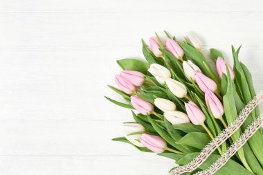 Beyaz ve Pembe Lale buketi Beyaz ahşap zemin üzerinde dantel ile dekore edilmiştir. Kopya alanı, üstten görünüm