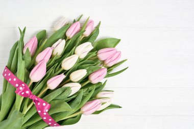 Pembe ve Beyaz Lale buketi kurdele ile süslenmiş. Kopya alanı, üstten görünüm