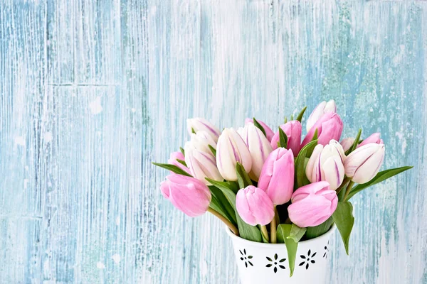 Pink tulips bouquet in white vase on light blue  background. Holiday background, copy space. Valentine Day, Mothers day, birthday concept.