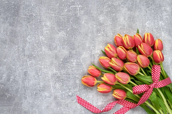 Red tulips bouquet decorated with ribbon on gray background. Cop — Stock Photo, Image