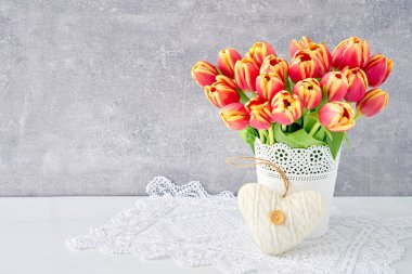 Beyaz vazoda kırmızı lale buketi Tekstil kalp ile dekore edilmiştir. V