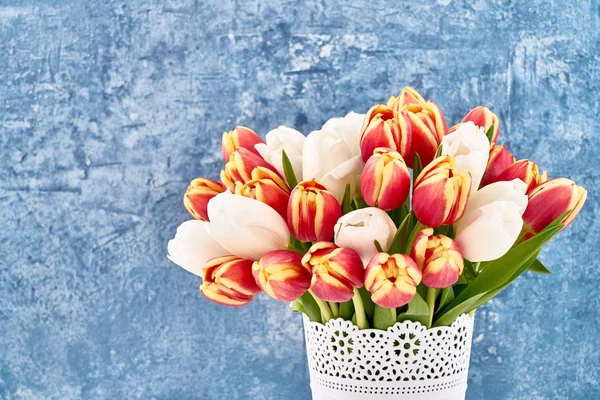 Buquê de tulipas vermelhas e brancas em vaso de flores brancas em azul brilhante — Fotografia de Stock