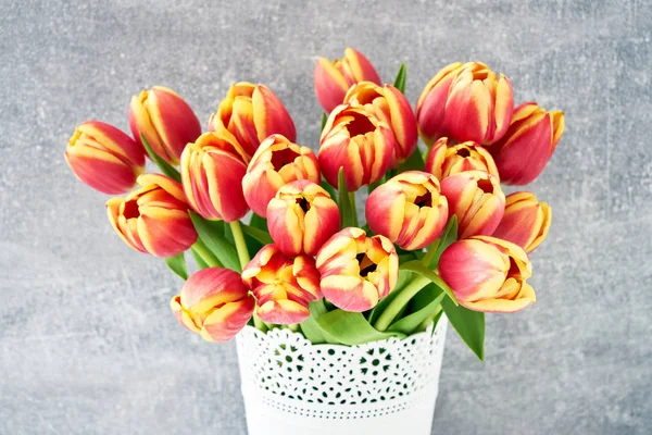 Czerwone tulipany bukiet w białe kwiaty pot na szarym tle. Holi — Zdjęcie stockowe
