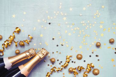 Mavi arka planda iki şampanya şişesi ve altın konfeti. Noel 'in yatışı, yeni yıl, Purim kutlama konsepti. Boşluğu kopyala, üst görünüm.