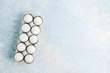 Mavi arka planda beyaz yumurtalı bir kutu. Flatlay, boşluğu kopyala