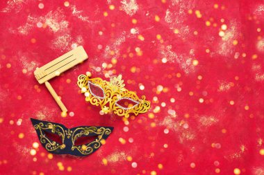 Karnaval maskesi ve parlak kırmızı arka planda ahşap kama. Purim Karnavalı 'nın düz yatışı konsepti.