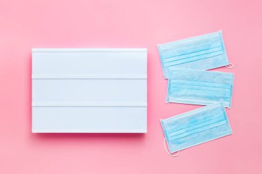 Pembe arka plandaki yazı için üç tıbbi koruyucu maske ve beyaz dijital ekran. Sağlık ve tıbbi konsept. Üst görünüm, metin için boşluk kopyala