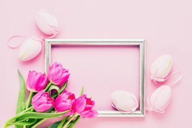 Paskalya geçmişi. Süslü pembe Paskalya Yumurtaları ve pembe arka planda lale çiçekleri. Üst görünüm, metin için boşluk kopyala. Paskalya kutlaması kavramı.
