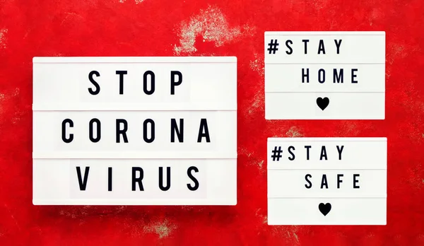 STOP CORONA VIRUS, STAY HOME and STAY SAFE written in light box on bright red background. Healthcare and medical concept. Top view. Quarantine concept.