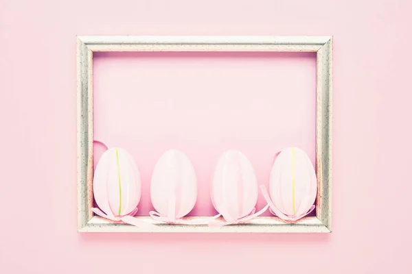 Easter background. Decorative pink Easter Eggs and tulip flowers on pink background. Top view, copy space for text. Easter celebration concept.