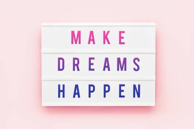 Pembe arka planda ışık kutusuna yazılan rüyaları gerçekleştir. Motivasyon alıntısı. Üst görünüm.