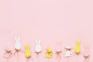 Paskalya süsü. Renkli ahşap Paskalya yumurtaları ve pembe arka planda tavşan. Tebrik kartı. Üst görünüm, alanı kopyala