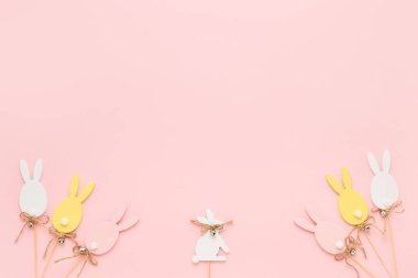 Paskalya süsü. Renkli ahşap Paskalya yumurtaları ve pembe arka planda tavşan. Tebrik kartı. Üst görünüm, alanı kopyala