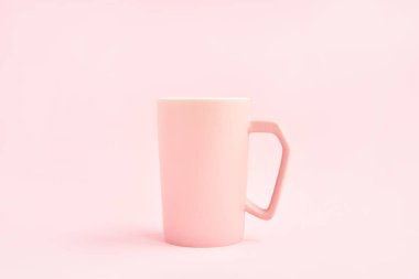 Pembe arka planda pembe bir fincan kahve. Uzayı metin için kopyala. Model