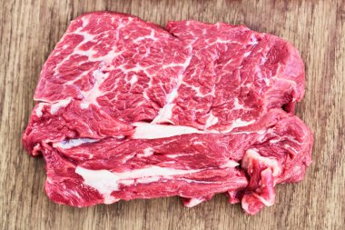 Tahta kesme tahtasına çiğ biftek dilimi. Üst manzara, düz uzanma.