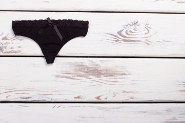 Ahşap arka plan üzerinde ipek yay ile siyah tanga.