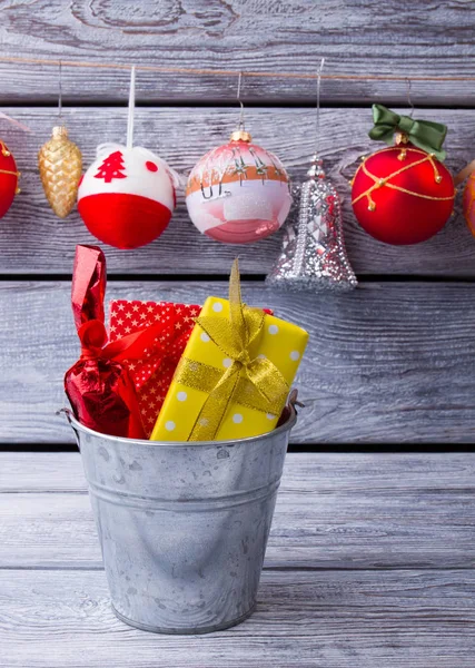 Seau avec des cadeaux sur fond de boules de Noël . — Photo