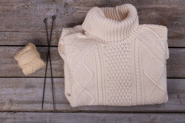 İplik ve örme iğne ile beyaz örgü kazak. 