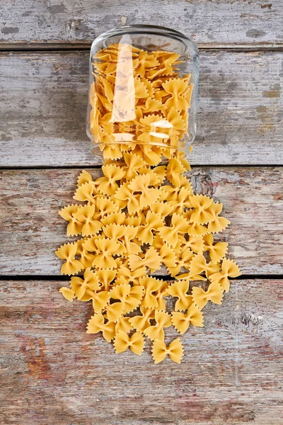 Schöne trockene Pasta aus einem Glas verstreut. — Stockfoto