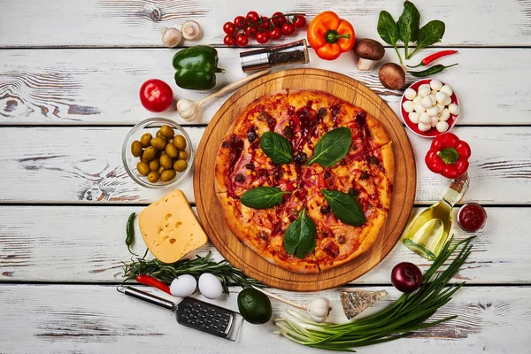 Pizza surrounded with fresh vegetables.