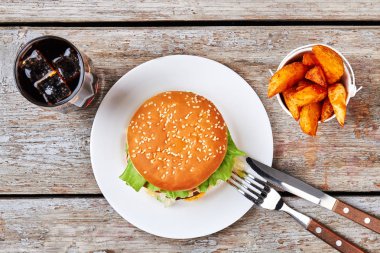 İçecek, patates kızartması, hamburger plaka üzerinde.