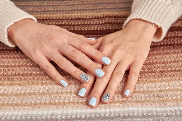 Beautiful blue manicure with rhinestones on knitted gradient bac