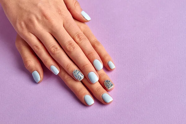 Kobiecych rąk z schludny manicure na fioletowym tle. — Zdjęcie stockowe