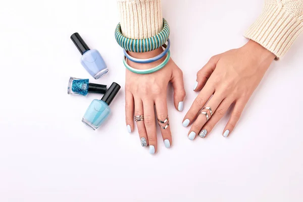 Trandy female manicure with blue bracelets on a white background