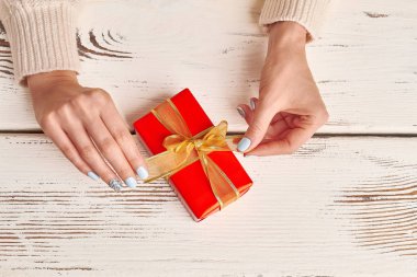 Bakımlı eller ahşap arka plan üzerinde kırmızı bir hediye ile