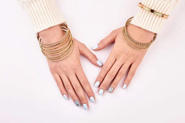 Mãos femininas com pulseiras de ouro e manicure azul . — Fotografia de Stock