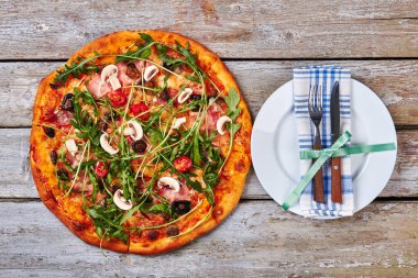 Pizza, porselen tabak, çatal bıçak takımı.