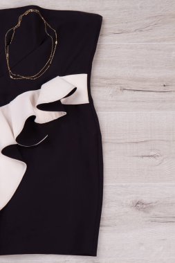Siyah ve beyaz elbise ile altın zincir.