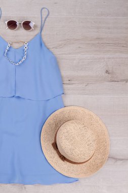 Hasır şapka ve beyaz güneş gözlüğü ile güzel bir mavi elbise.