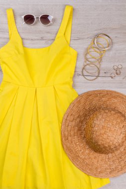 Hasır şapka ve aksesuarları ile sarı elbise. 