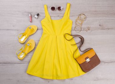 Ahşap arka plan üzerinde aksesuarları ile sarı elbise. 