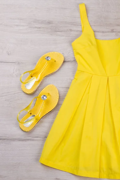 Vestido amarelo brilhante e sandálias em um fundo leve . — Fotografia de Stock