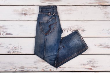 Ahşap arka plan üzerinde koyu mavi jeans katlanmış.