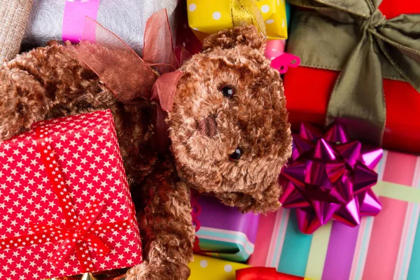 Teddy bear laying among gifts