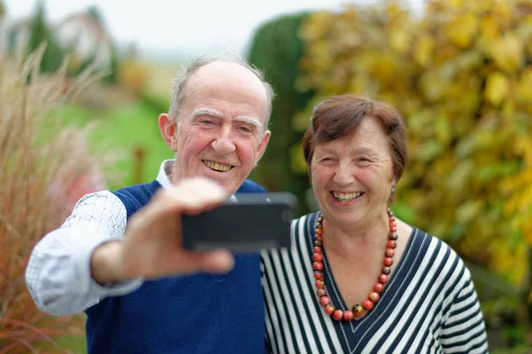 Heureux couple aîné coller les uns aux autres et faire selfie — Photo