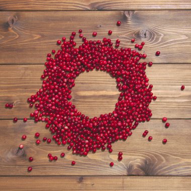 Kahverengi ahşap zemin üzerinde kırmızı kızılcık yuvarlak çerçeve