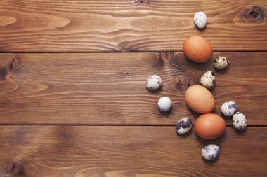 Tahta arka planda tavuk ve bıldırcın yumurtası.
