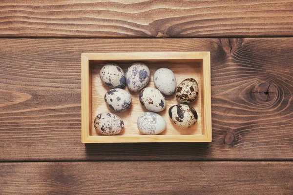 Quail eggs in wooden box on wooden background