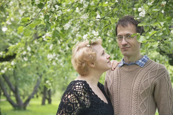 Mann und Frau mittleren Alters im blühenden Apfelbaumgarten. — Stockfoto