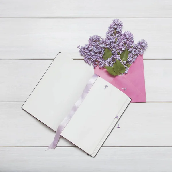 Clean sheets notepad with lilac flowers in envelope