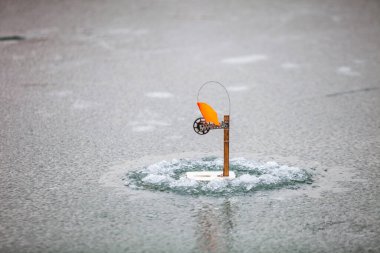 Donmuş bir nehirde kış balıkçılığı. Bayraklarla uğraş