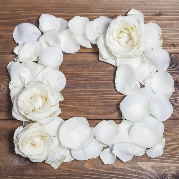 White roses frame on brown wooden background