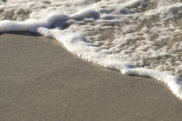 Espuma de la ola del mar en la arena — Foto de Stock