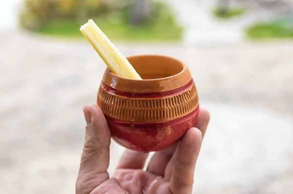 Une tasse d'argile avec du jus de coco de rhum et un morceau d'épi de sucre en ha — Photo