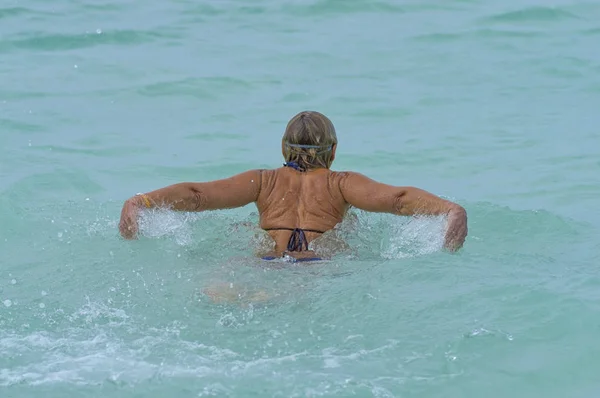 Niña nadador nada en el estilo del mar de la mariposa, vista trasera — Foto de Stock