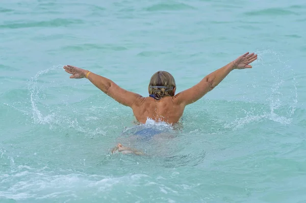 Niña nadador nada en el estilo del mar de la mariposa, vista trasera — Foto de Stock